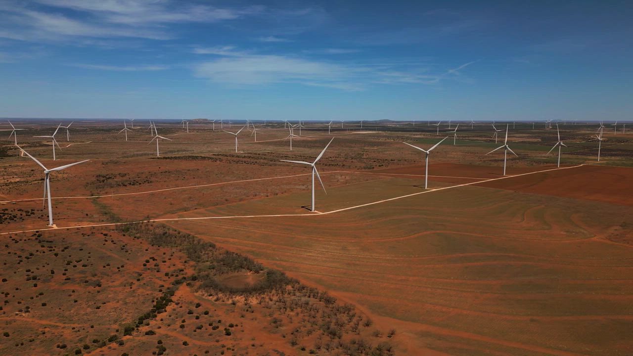Wind turbines on red earth under a clear sky