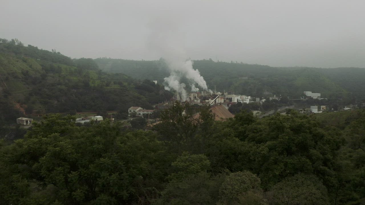 Factory in a green valley with steam rising