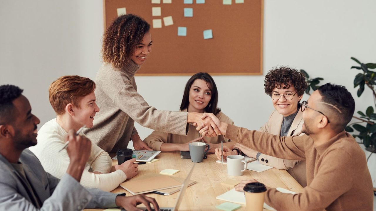 Small team shaking hands around a meeting table
